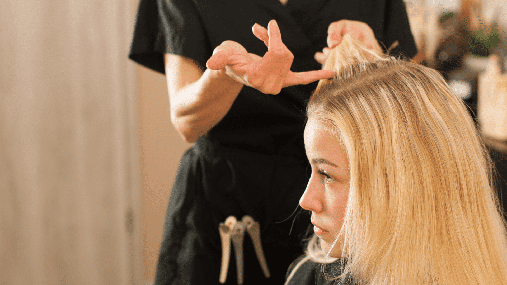Hairstylist working on a blonde woman's hair in a salon setting.
